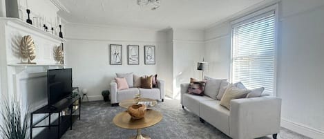 A living room with a fireplace, two sofas, a coffee table, and a television.