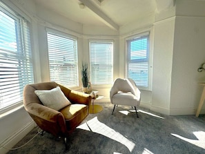 A room with two armchairs, a small table, and a potted plant.