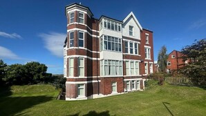 A multi-story building with a corner tower, large windows, and a well-maintained lawn.