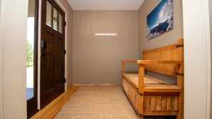 A hallway with a wooden bench, a coat rack, and a door with glass panels.