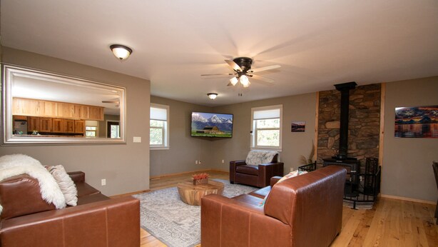 A spacious living room with a fireplace, leather sofas, a wooden coffee table, and a stone accent wall.