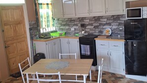 Una cucina con tavolo da pranzo, sedie, pensili, un forno a microonde, un fornello e un frigorifero.