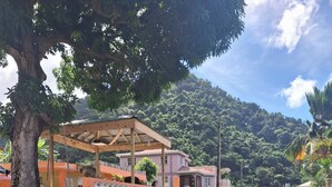 Una strada con un gazebo in legno, un edificio rosa e una montagna sullo sfondo.