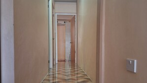 Un corridoio con pavimento in legno decorato, pareti beige e una luce a soffitto.