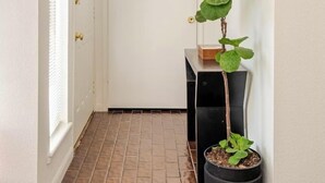 A hallway with a potted plant, a mirror, and a door. - A Modern & Cozy Townhome with good vibes (Houston)