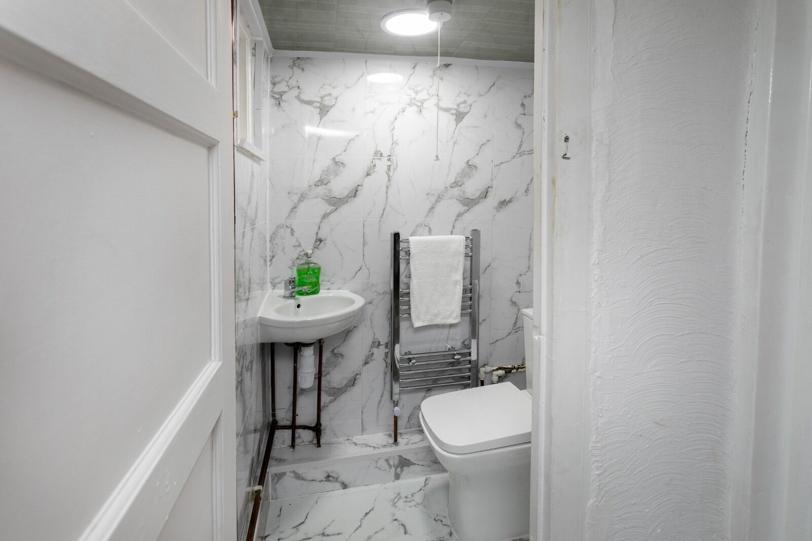 A bathroom with a white sink, a toilet, and a towel rack.