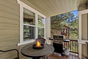 Un espacio al aire libre techado con una mesa redonda, una chimenea y una parrilla.