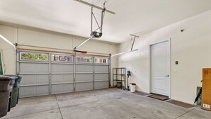 Un garage doté d’une grande porte, d’un sol en béton et d’un luminaire fixé au plafond.