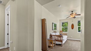 Une chambre à coucher avec un lit, une table de chevet et un ventilateur de plafond.