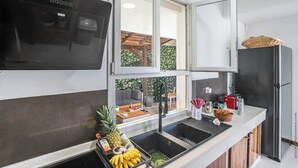 A modern kitchen with a built-in oven, a large window, and a refrigerator. - Stunning Pool Villa – Treasure of the Bay (La Trinité)