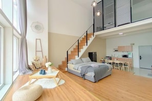 A modern apartment with a loft bedroom, a staircase, a kitchen, and a dining area. - Empire City Signature Duplex Suites (Petaling District)