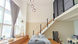 Un dormitorio moderno con cama, escalera, zona de comedor y cocina.