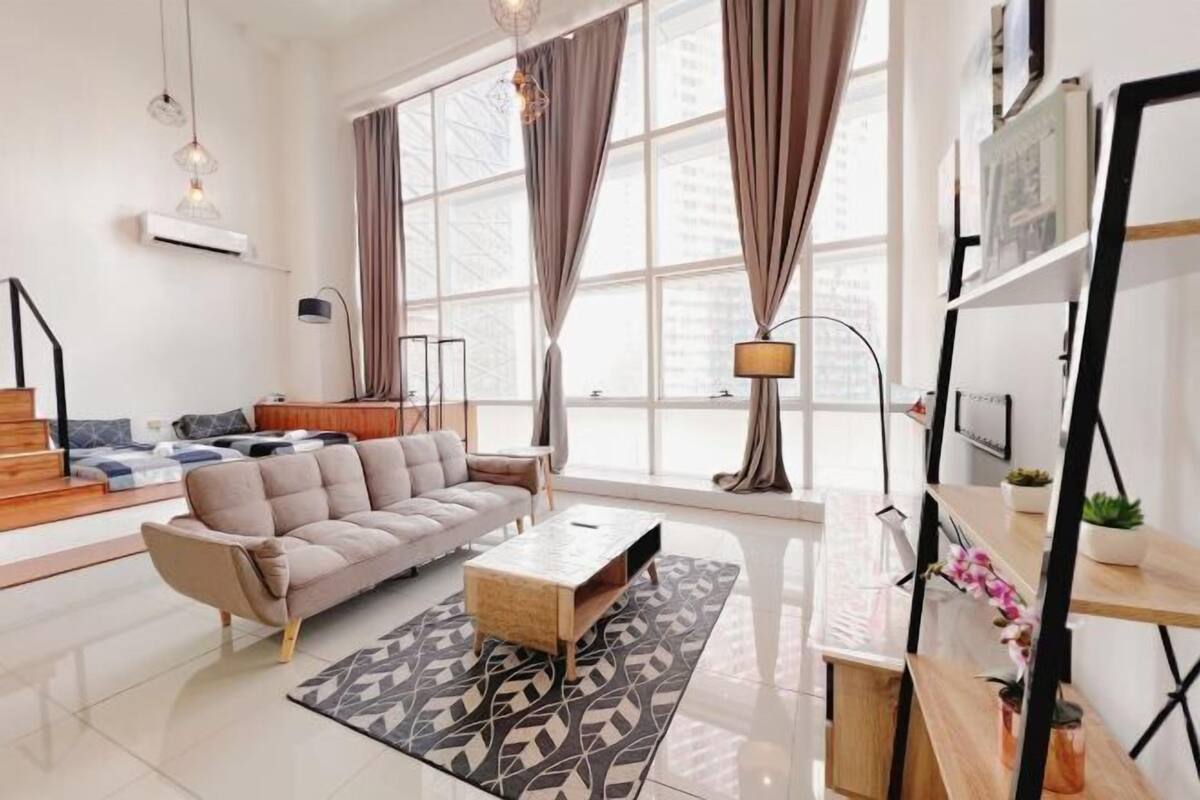 A modern living room with a sofa, coffee table, and a large window with curtains.