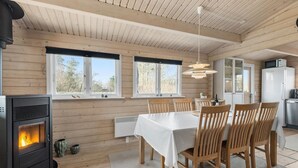 Un intérieur en bois comprenant un coin repas, une cuisine et un poêle à bois.