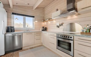 Une cuisine moderne avec des murs en bois, des appareils électroménagers en acier inoxydable et une grande fenêtre.