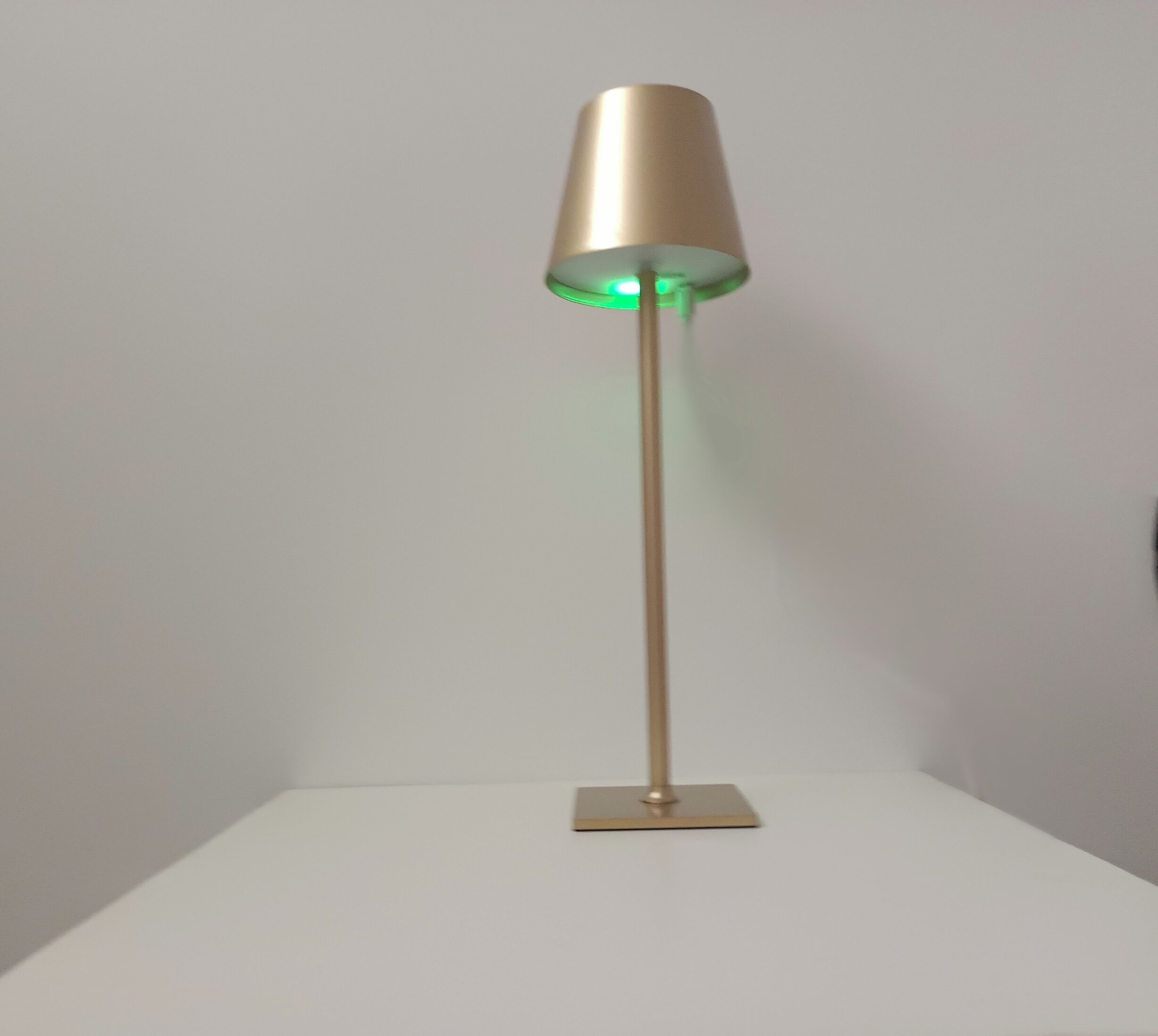 A floor lamp with a metallic finish and a green light.