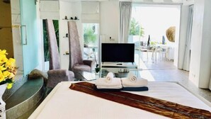 A modern hotel room with a bed, a television, a seating area, and a view of the outdoors. - Samui Sky Pool Villa (Koh Samui)