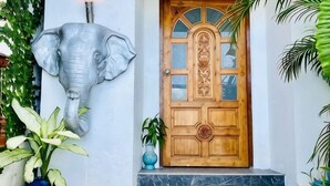 A wooden door with glass panels and a decorative elephant head sculpture. - Samui Sky Pool Villa (Koh Samui)