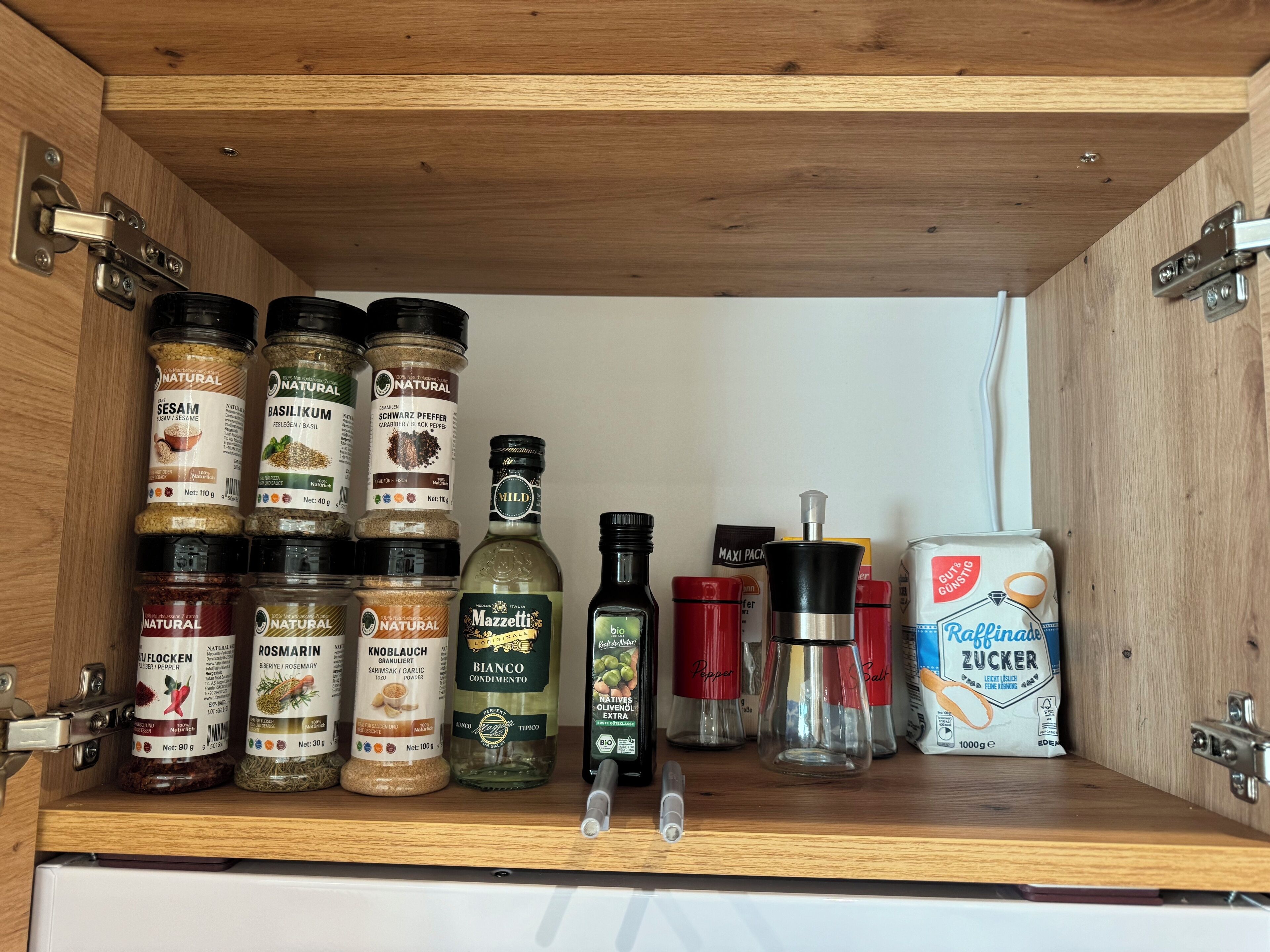 Un garde-manger contenant divers produits alimentaires, notamment des épices, des condiments et des huiles de cuisson.