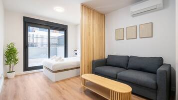 A modern living room with a grey sofa, a wooden bench, a small table, and a potted plant.