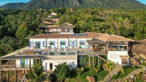 A resort with multiple buildings, a swimming pool, and a mountainous backdrop.