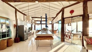 A spacious kitchen with a large island, wooden beams, and a view of the ocean.