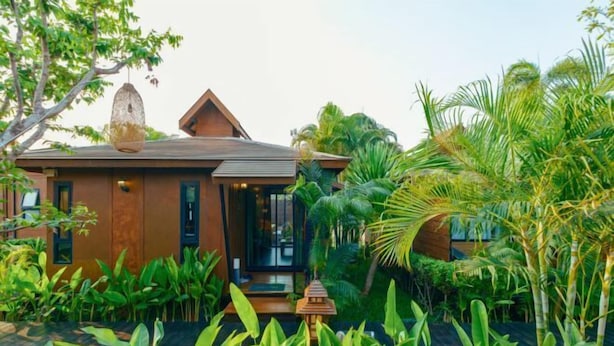 A modern house with a sloped roof, surrounded by lush tropical plants and a wooden deck. - R1 Resort Rajapruek Chiangmai (Hang Dong)