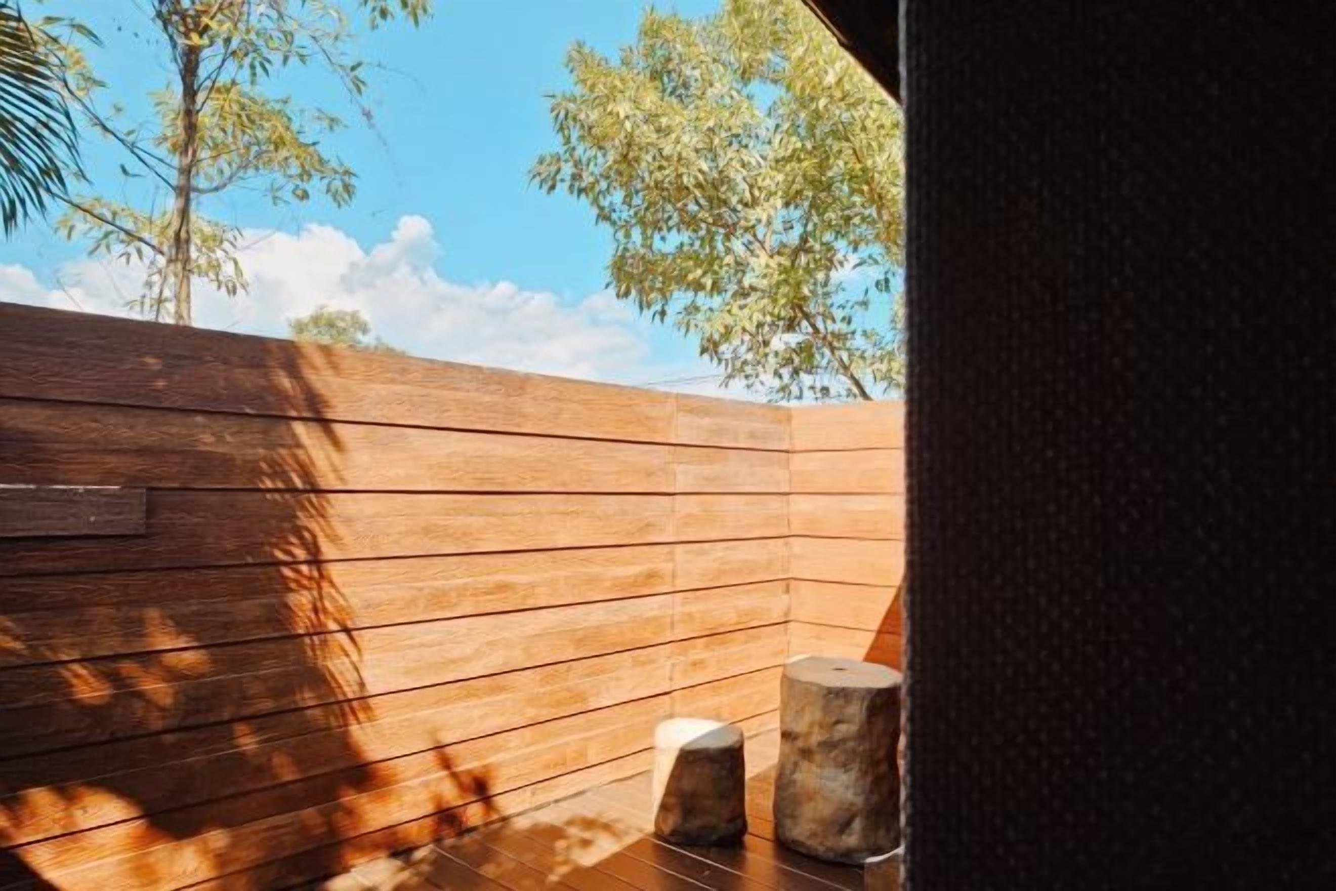 A wooden deck with a view of trees and sky.