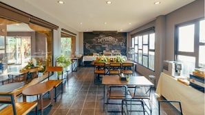 A modern cafe with wooden tables and chairs, a chalkboard wall with 'COFFEE BELT' written on it, and large windows allowing natural light. - R1 Resort Rajapruek Chiangmai (Hang Dong)