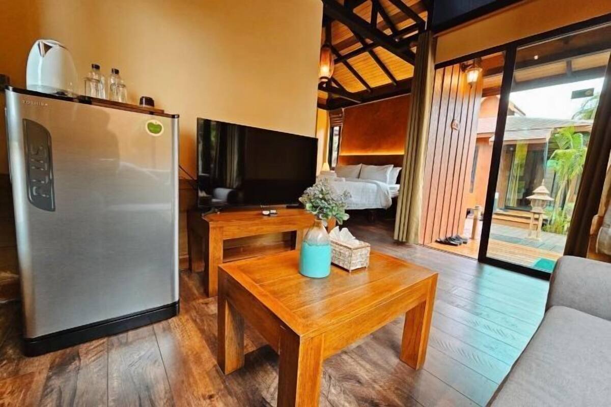 Habitació moderna amb una taula de fusta, televisió, llit i nevera.