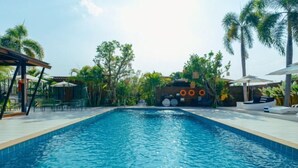A swimming pool with a tiled edge, surrounded by palm trees and outdoor seating. - R1 Resort Rajapruek Chiangmai (Hang Dong)