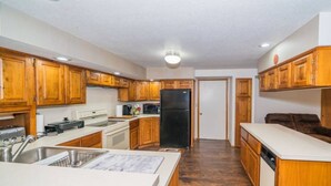 Una cocina compacta con armarios de madera, un refrigerador negro y una encimera blanca.
