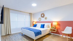 Una camera d'albergo con un letto, comodini, una TV e una finestra con tende.