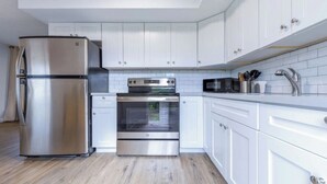 Una cucina moderna con elettrodomestici in acciaio inossidabile, mobili bianchi e zoccolo di piastrelle.