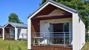 Eine moderne, eingeschossige Holzhütte mit einer Holzterrasse und großen Fenstern.