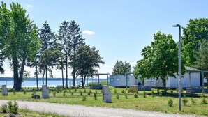 Ein Campingplatz mit Wohnmobilen, einem Kiesweg und einem See im Hintergrund.