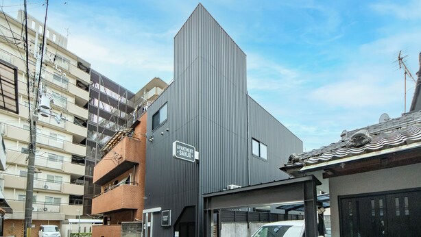 A modern building with a vertical design, a sign indicating it is an apartment complex, and a traditional roof style. - Apartment Sanjo (Nara City)