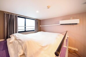 A hotel room with a bed, window, air conditioning unit, and a curtain. - Apartment Sanjo (Nara City)