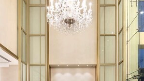 A spacious lobby with a large chandelier, tall glass walls, and a patterned rug. - The Leela Bhartiya City Bengaluru (Bengaluru)