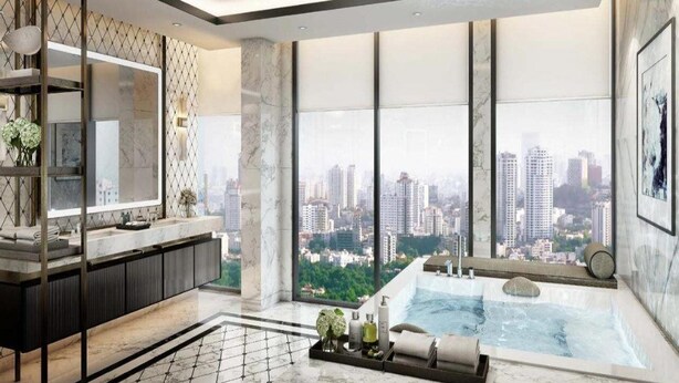 A modern bathroom with a large bathtub, a vanity with a mirror, and a city view through large windows. - The Leela Bhartiya City Bengaluru (Bengaluru)