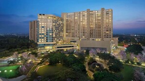 A high-rise hotel with multiple floors, a well-lit lobby, and a landscaped garden area. - The Leela Bhartiya City Bengaluru (Bengaluru)