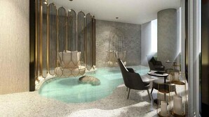 A modern indoor pool area with seating and a decorative wall. - The Leela Bhartiya City Bengaluru (Bengaluru)