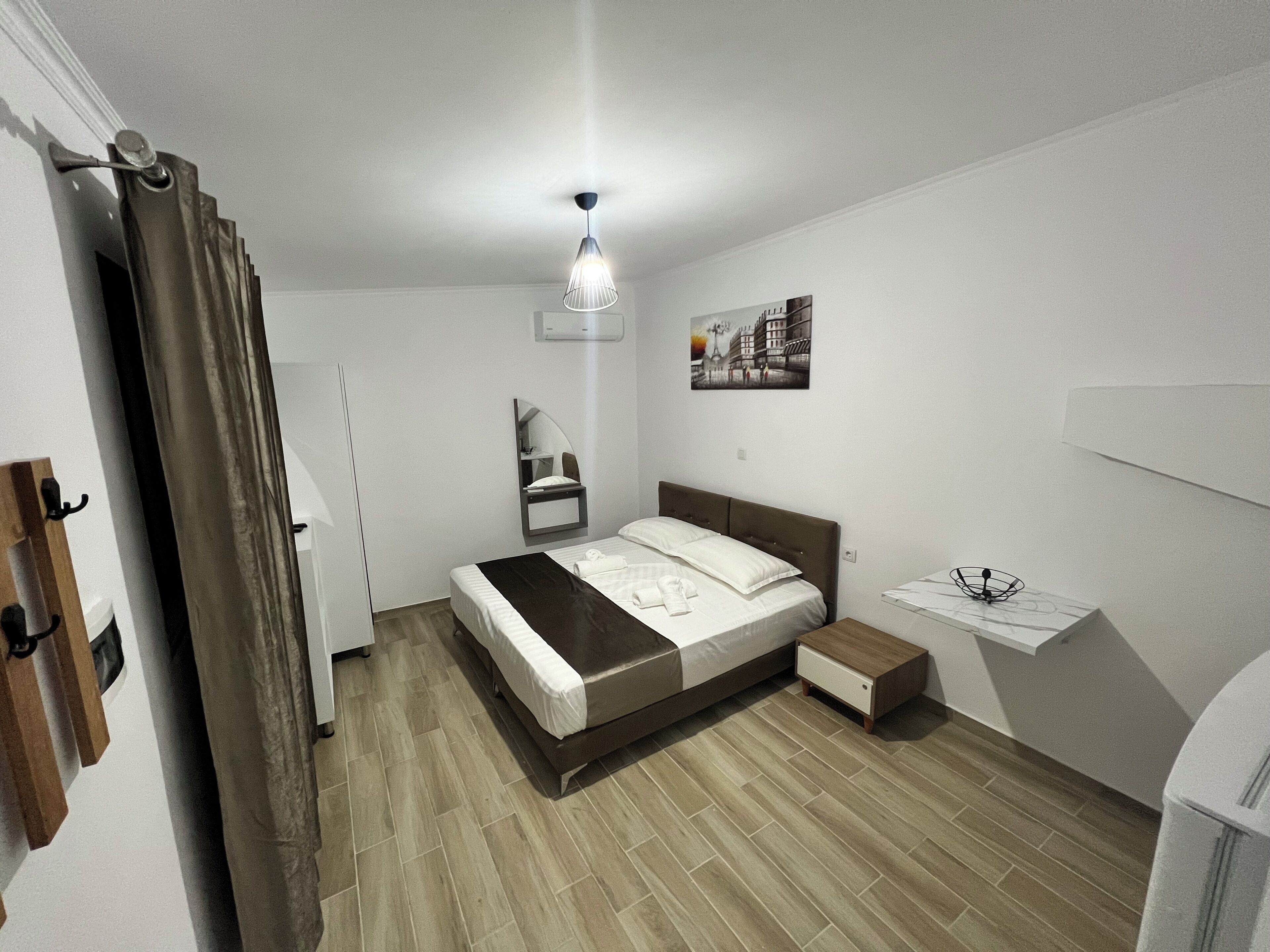 A bedroom with a bed, bedside table, and a hanging light fixture.