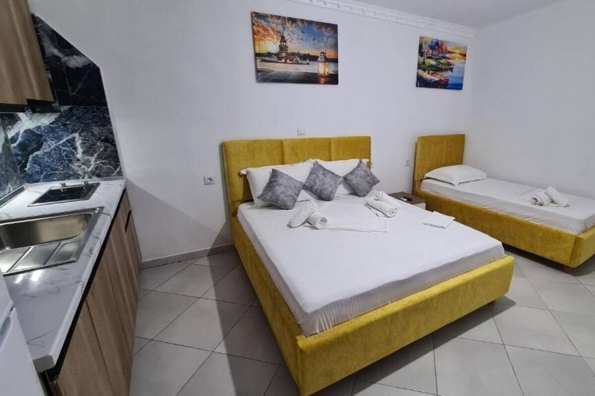 A hotel room with two beds, a kitchenette, and artwork on the walls.