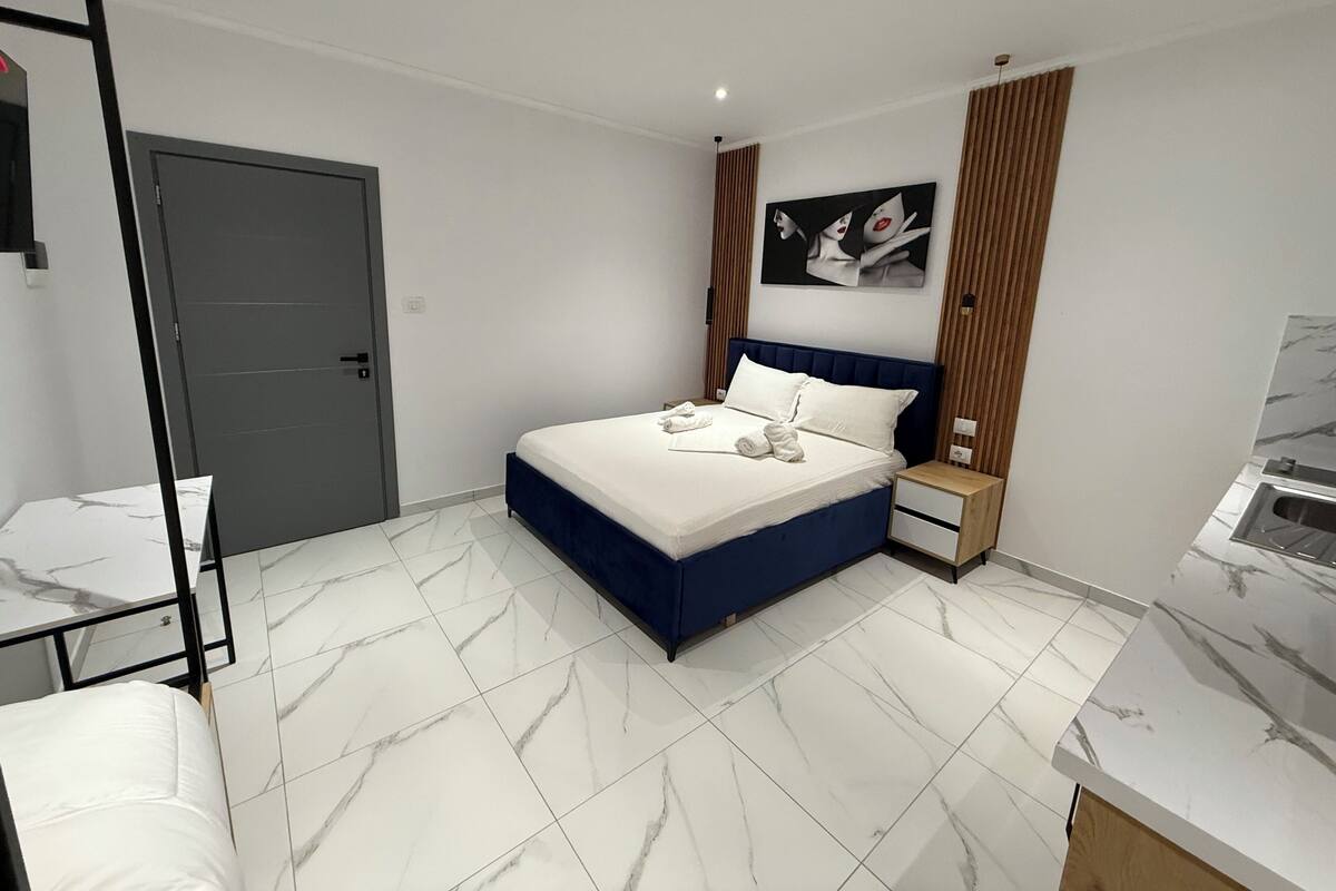 A modern bedroom with a bed, bedside table, and a door.