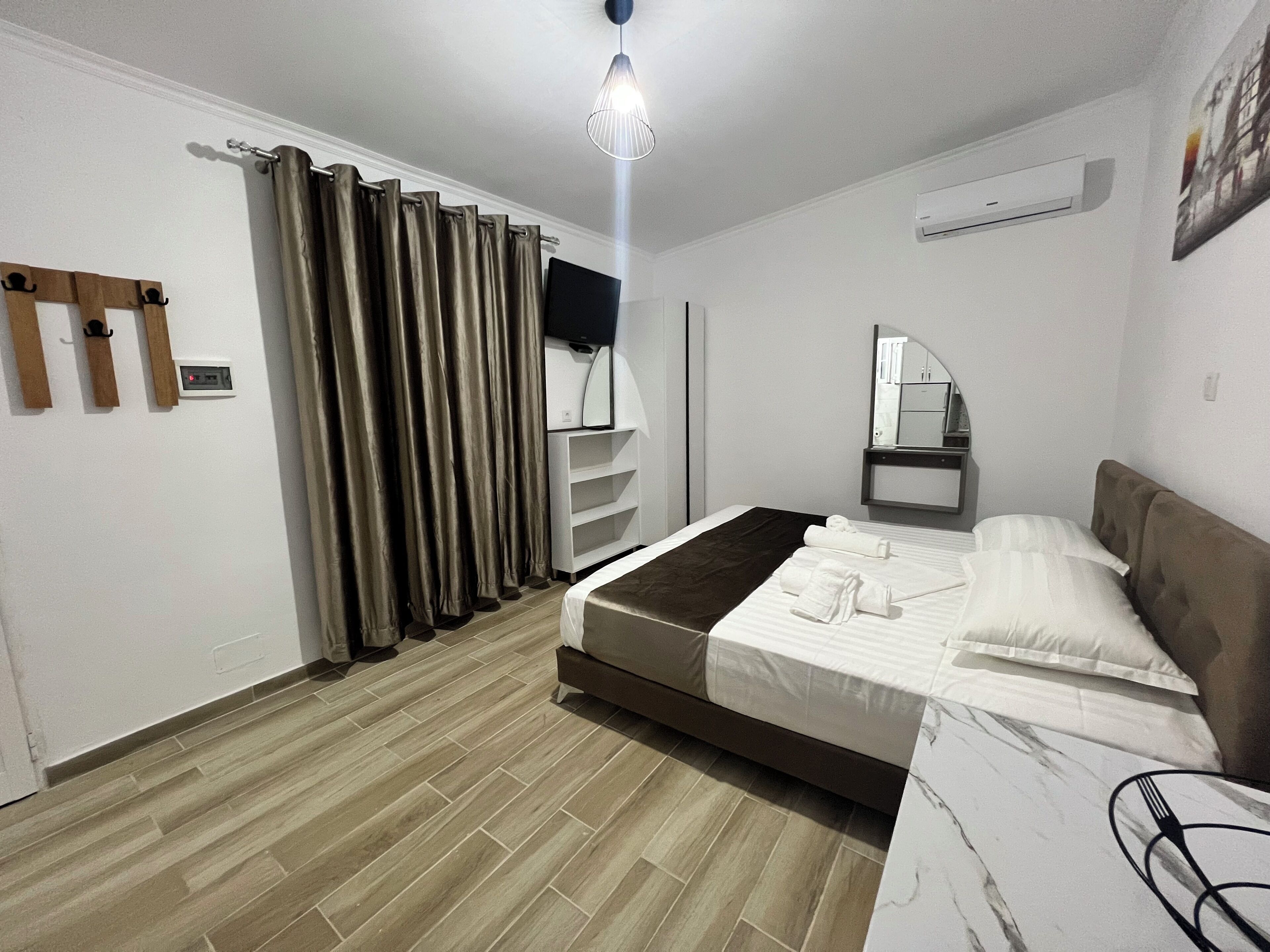Ein modernes Hotelzimmer mit Bett, Flachbildfernseher, Spiegel und einer Holzhilfe.