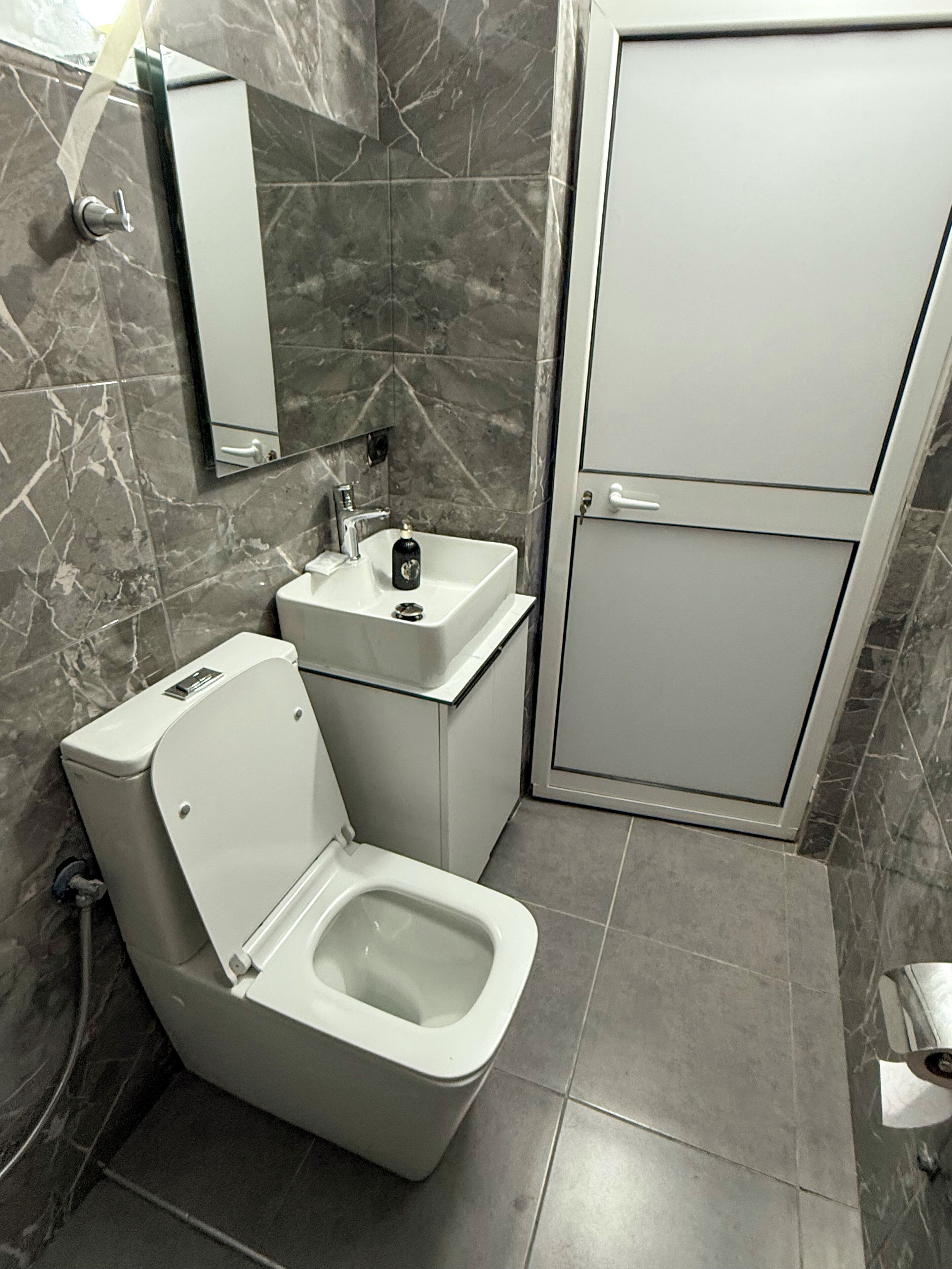 A modern bathroom with a toilet, sink, and mirror.