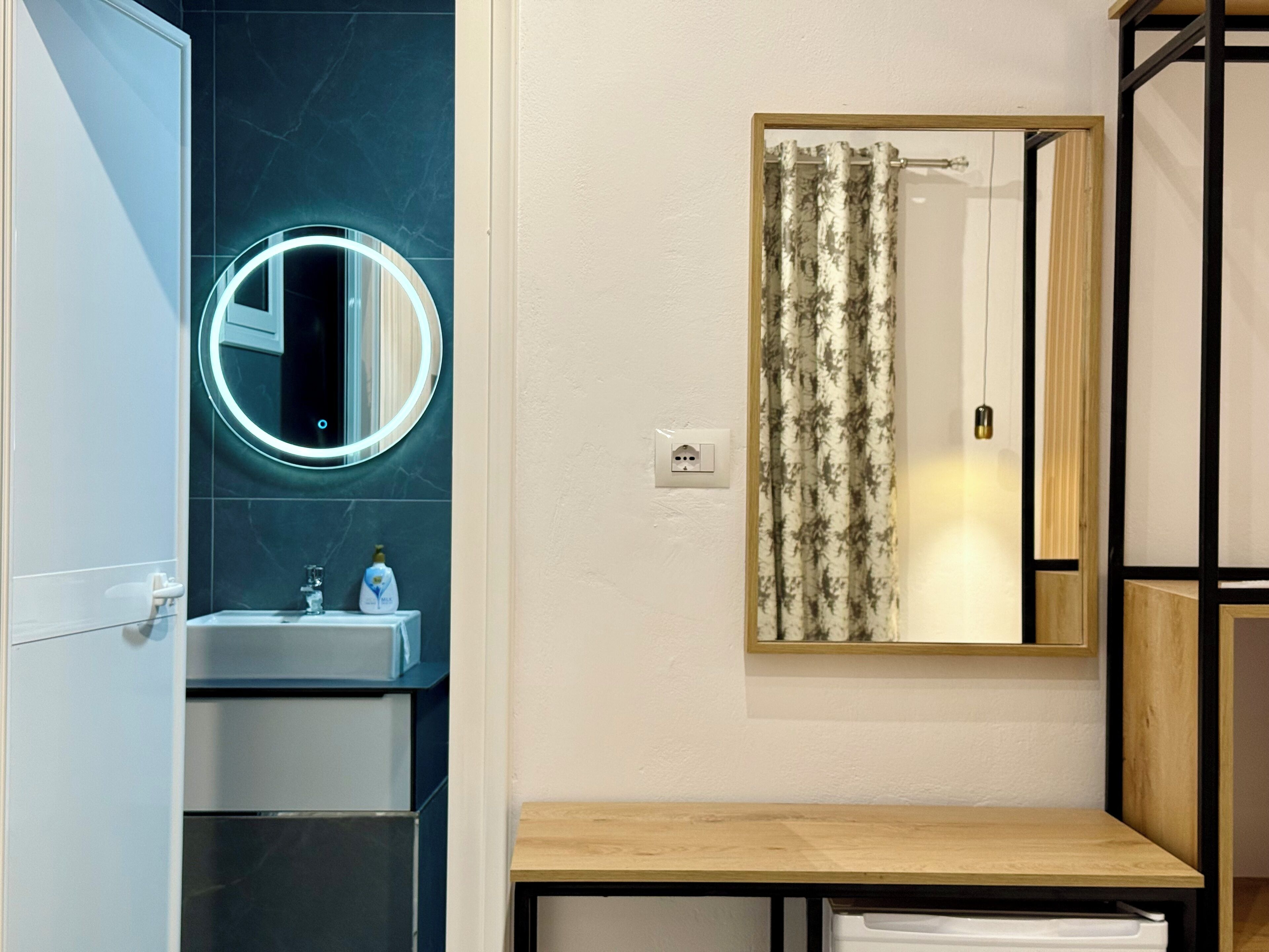 Une salle de bain avec un miroir rond, un lavabo, des toilettes et un rideau de douche.