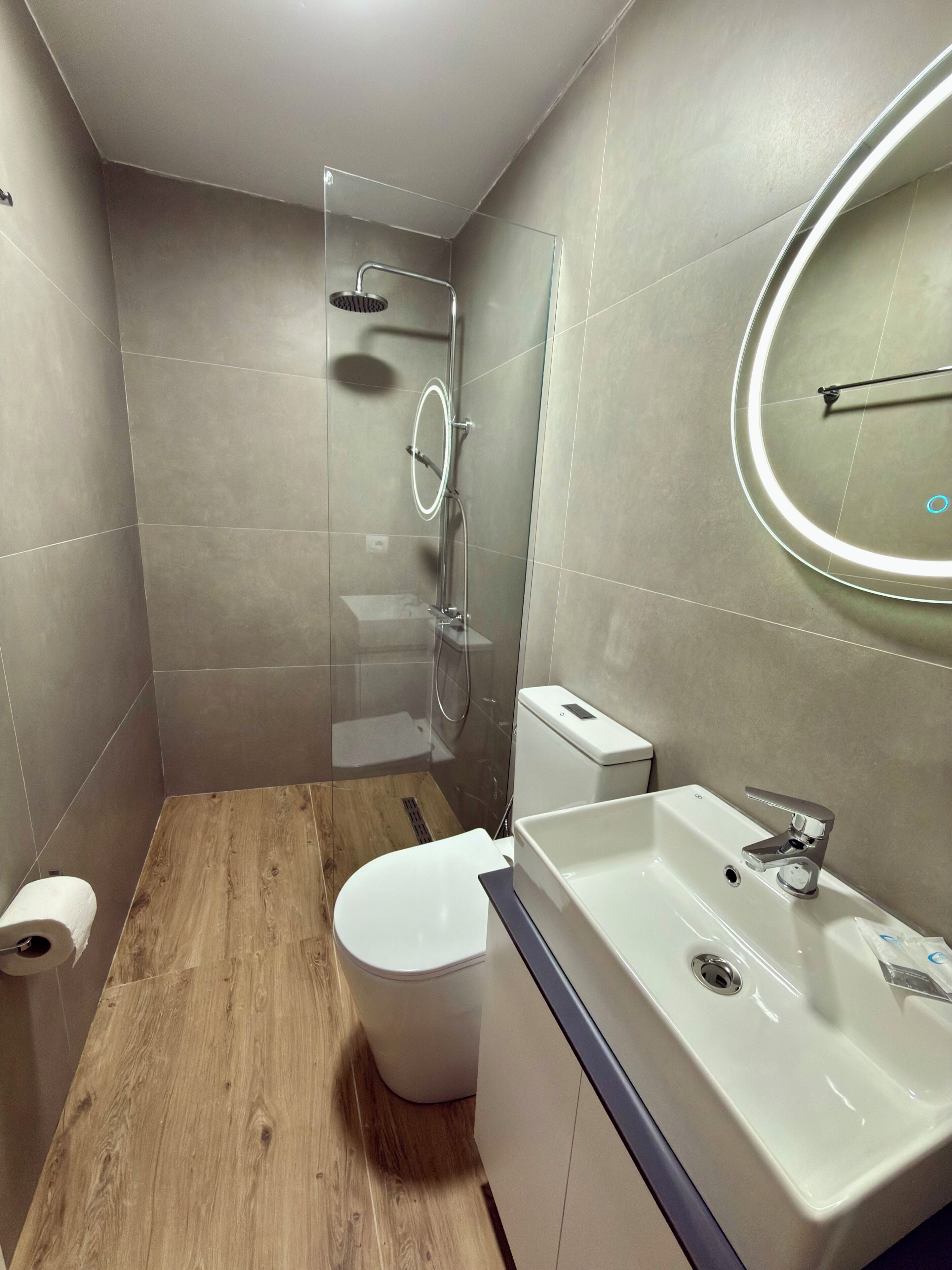 A modern bathroom with a shower, toilet, and sink.