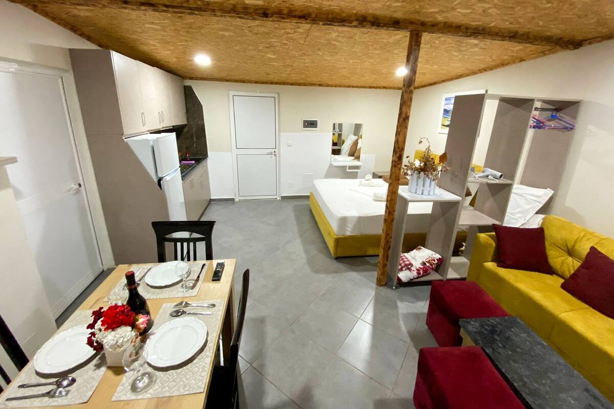 A compact living space with a dining area, kitchenette, and a bed.